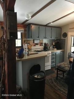 kitchen with decorative backsplash, dark wood-type flooring, kitchen peninsula, and gas range gas stove