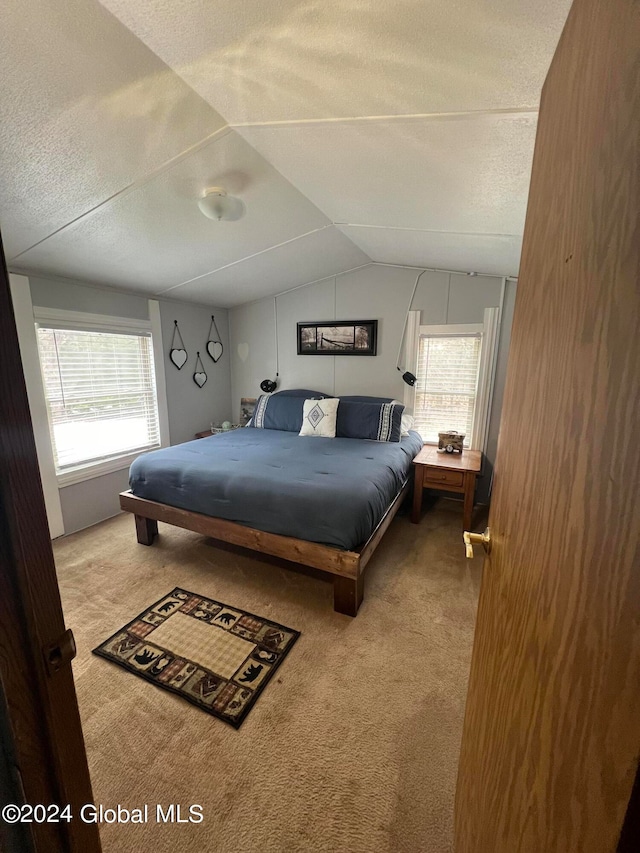 bedroom featuring light colored carpet, a textured ceiling, and lofted ceiling