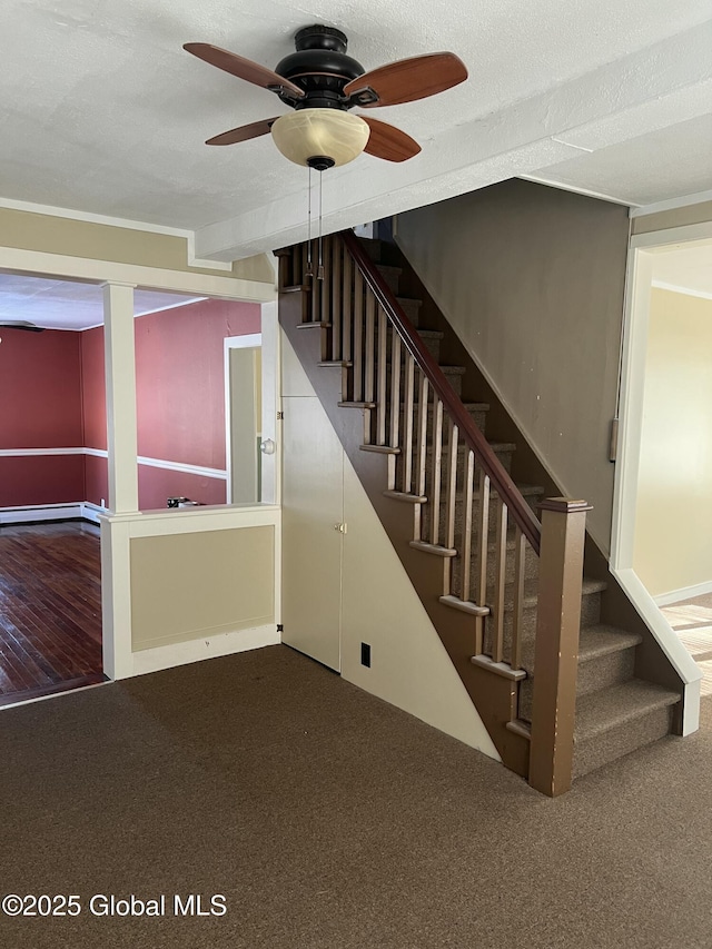 staircase with ceiling fan, carpet flooring, a baseboard heating unit, and a textured ceiling