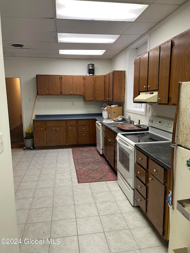 kitchen featuring a paneled ceiling, white appliances, sink, and light tile patterned floors