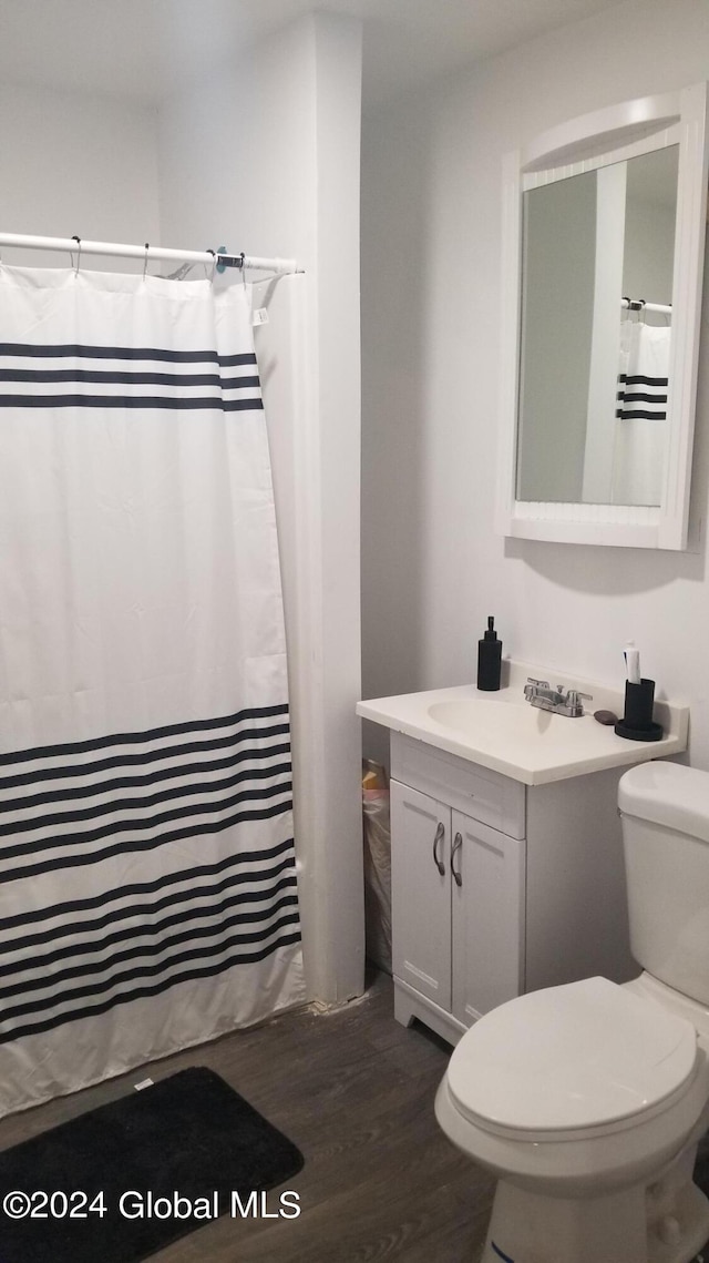 bathroom with wood-type flooring, vanity, toilet, and curtained shower