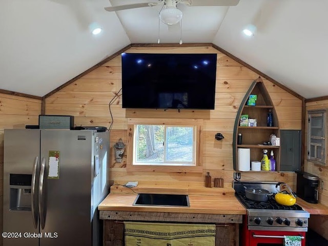 kitchen with appliances with stainless steel finishes, ceiling fan, wood walls, and vaulted ceiling