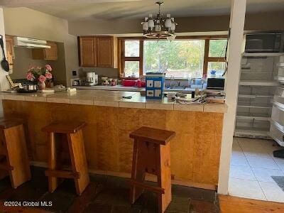 kitchen featuring a breakfast bar area, an inviting chandelier, and plenty of natural light