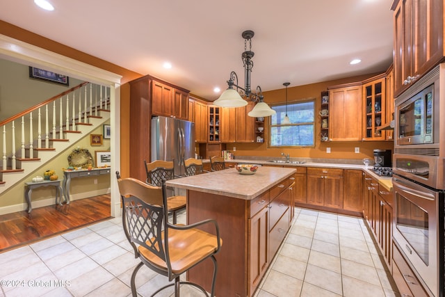 kitchen featuring a center island, appliances with stainless steel finishes, decorative light fixtures, and light tile patterned floors