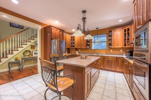 kitchen with light tile patterned floors, a breakfast bar area, a sink, stainless steel appliances, and light countertops
