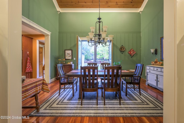 dining area featuring ornamental molding, a towering ceiling, an inviting chandelier, and wood finished floors