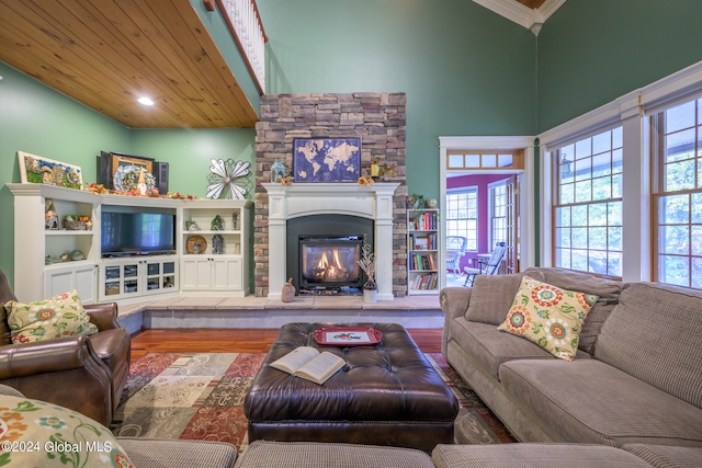 living room featuring a stone fireplace, hardwood / wood-style flooring, high vaulted ceiling, and wooden ceiling