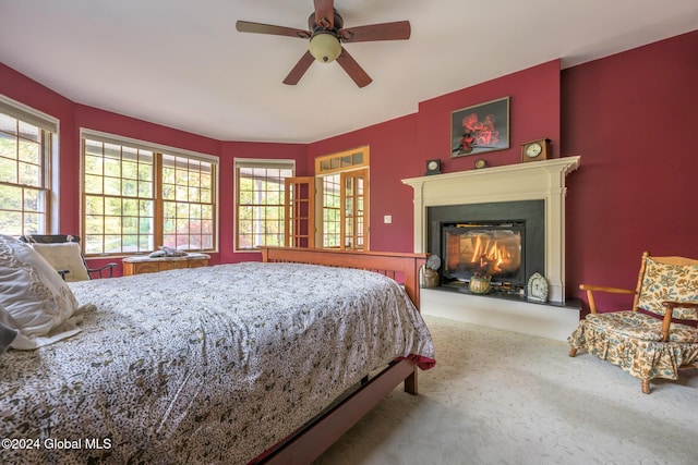 carpeted bedroom with a ceiling fan and a glass covered fireplace