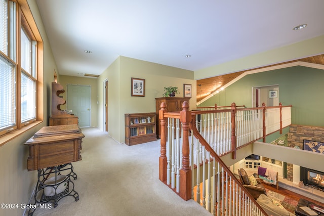 hallway with lofted ceiling and light colored carpet