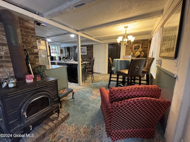 carpeted living area featuring a wood stove, an inviting chandelier, a textured ceiling, a sink, and brick wall
