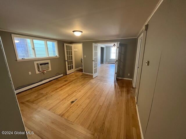 empty room with light wood-type flooring, plenty of natural light, a baseboard radiator, and a wall mounted air conditioner