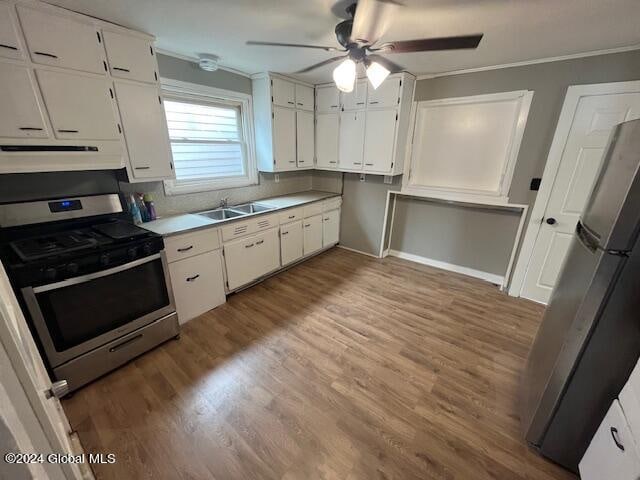 kitchen with stainless steel appliances, ornamental molding, hardwood / wood-style flooring, and white cabinetry