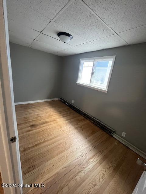 unfurnished room with a drop ceiling and light hardwood / wood-style flooring