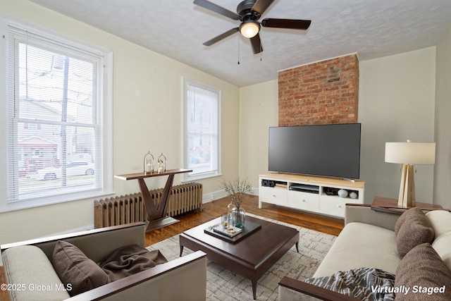 living area with radiator, wood finished floors, and a healthy amount of sunlight