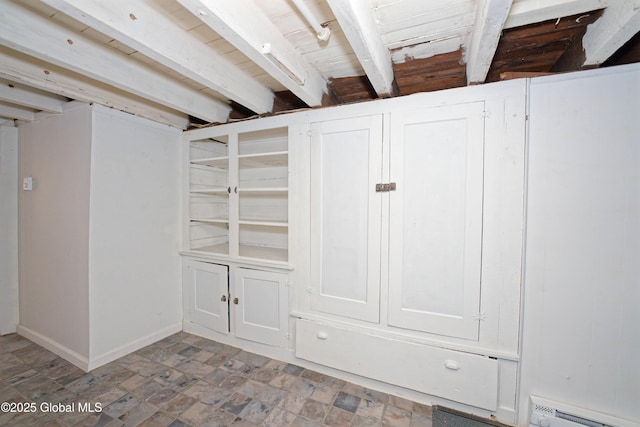 basement featuring stone finish flooring, baseboard heating, and baseboards