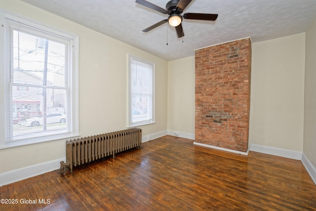 unfurnished room with ceiling fan, radiator, wood finished floors, and baseboards