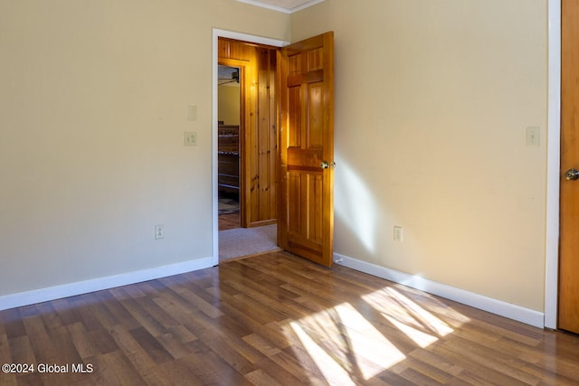 empty room featuring crown molding and dark hardwood / wood-style flooring