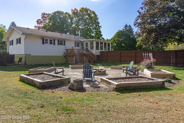 back of property with a yard, an outdoor fire pit, and a deck