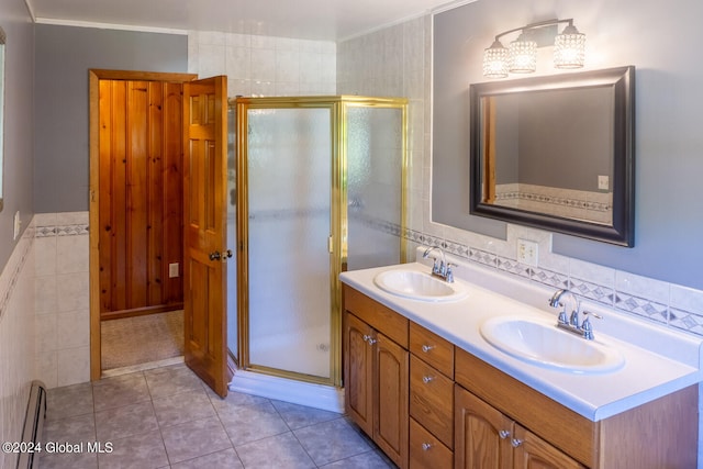 bathroom with a shower with door, ornamental molding, vanity, tile patterned floors, and tile walls