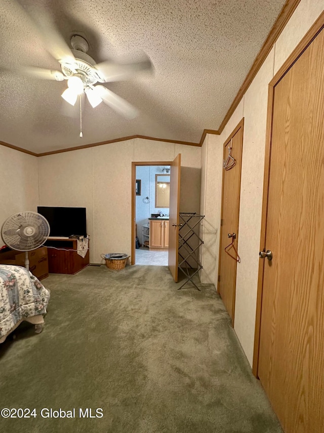 unfurnished bedroom featuring vaulted ceiling, carpet floors, a textured ceiling, ceiling fan, and crown molding