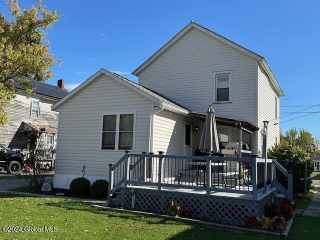 rear view of property featuring a lawn and a deck