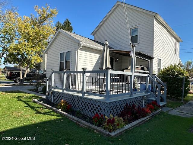 rear view of house featuring a wooden deck and a lawn