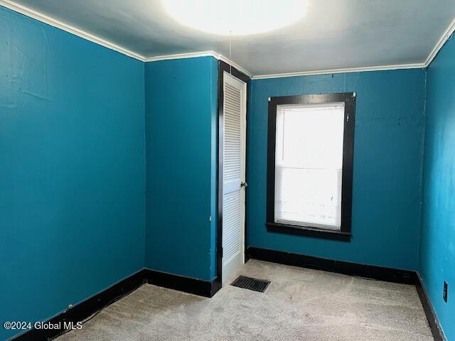 carpeted spare room featuring crown molding