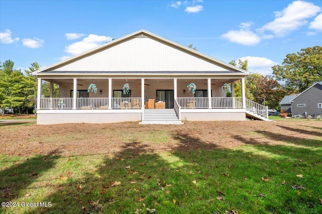 rear view of house featuring covered porch and a lawn