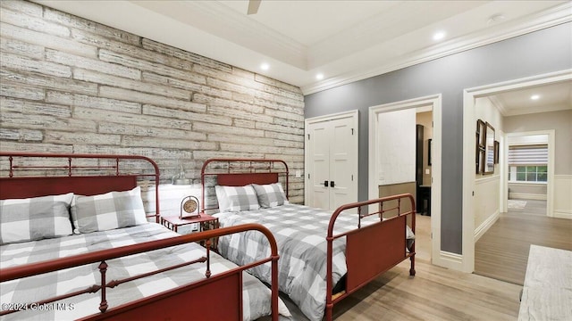 bedroom featuring a closet, light hardwood / wood-style floors, crown molding, and ceiling fan