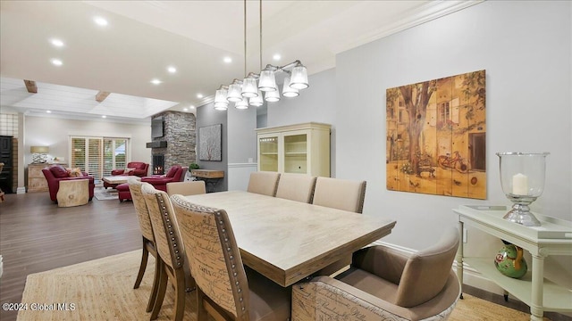 dining area featuring crown molding, hardwood / wood-style flooring, and a stone fireplace