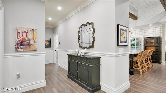 hall with light hardwood / wood-style floors, crown molding, and a healthy amount of sunlight