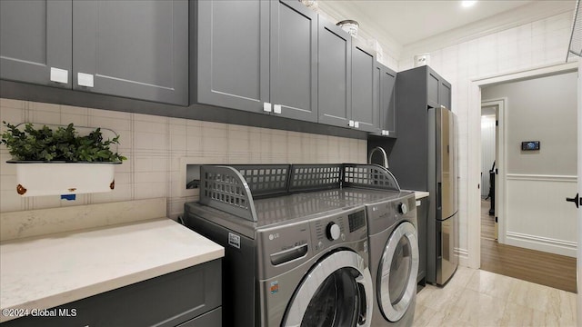 laundry room with cabinets, light hardwood / wood-style flooring, and washing machine and dryer