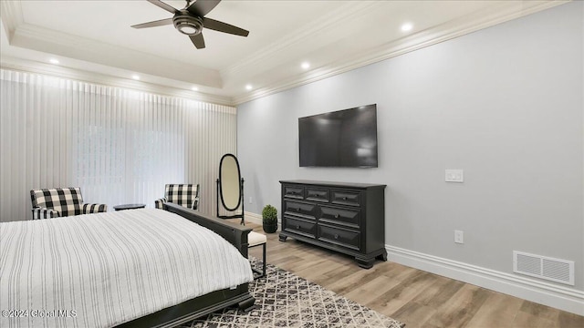 bedroom featuring ornamental molding, hardwood / wood-style floors, a tray ceiling, and ceiling fan