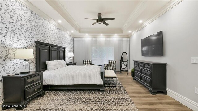 bedroom with hardwood / wood-style floors, a raised ceiling, crown molding, and ceiling fan