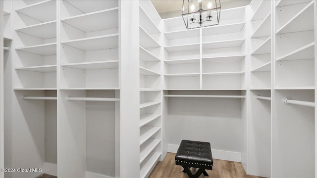 walk in closet featuring a notable chandelier and wood-type flooring