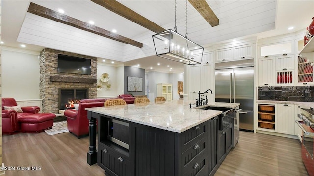 kitchen featuring a spacious island, beam ceiling, decorative light fixtures, white cabinetry, and appliances with stainless steel finishes