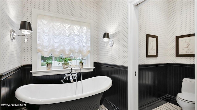 bathroom with a tub, toilet, and wooden walls