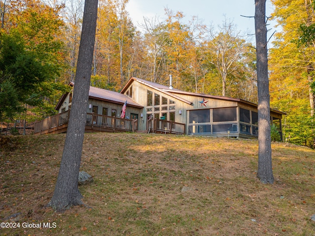 rear view of property with a sunroom and a deck