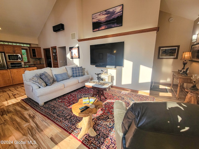 living room with light hardwood / wood-style flooring and high vaulted ceiling