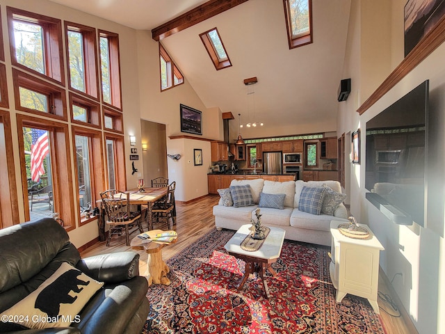 living room featuring a skylight, beam ceiling, high vaulted ceiling, hardwood / wood-style flooring, and a notable chandelier