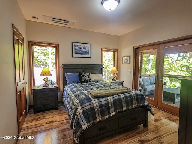 bedroom featuring french doors, access to outside, light hardwood / wood-style flooring, and multiple windows