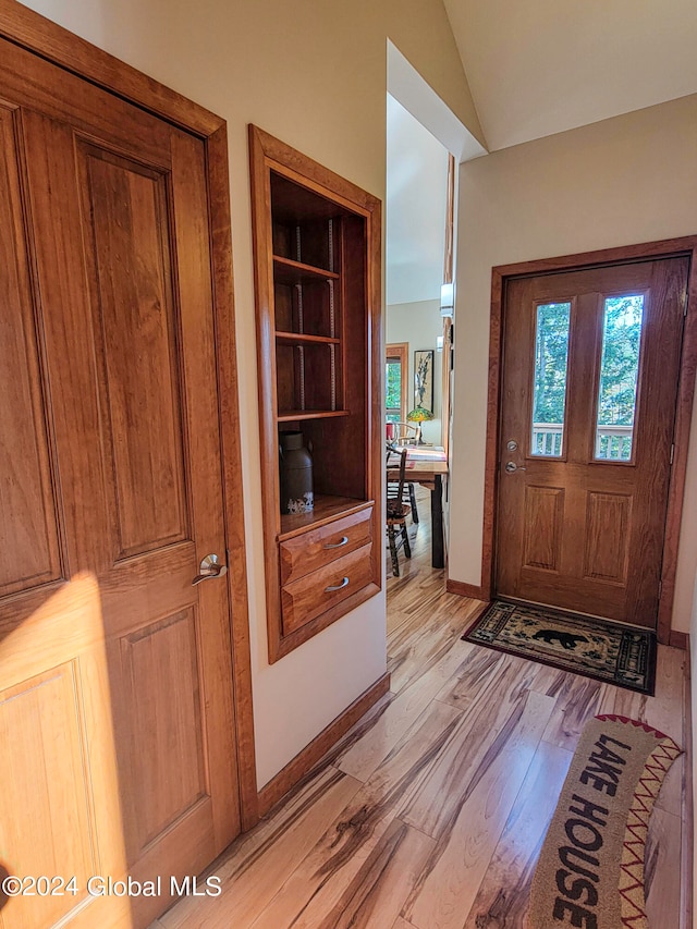 entryway featuring light wood-type flooring and vaulted ceiling