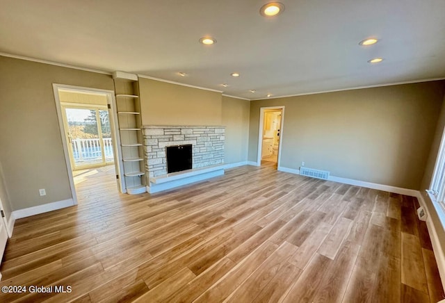 unfurnished living room featuring a fireplace, ornamental molding, and light hardwood / wood-style floors