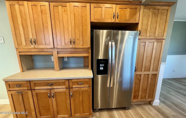 kitchen with stainless steel refrigerator with ice dispenser, light stone counters, and light wood-type flooring