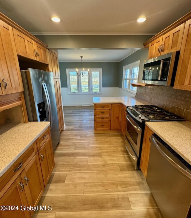 kitchen with crown molding, light hardwood / wood-style flooring, hanging light fixtures, backsplash, and stainless steel appliances