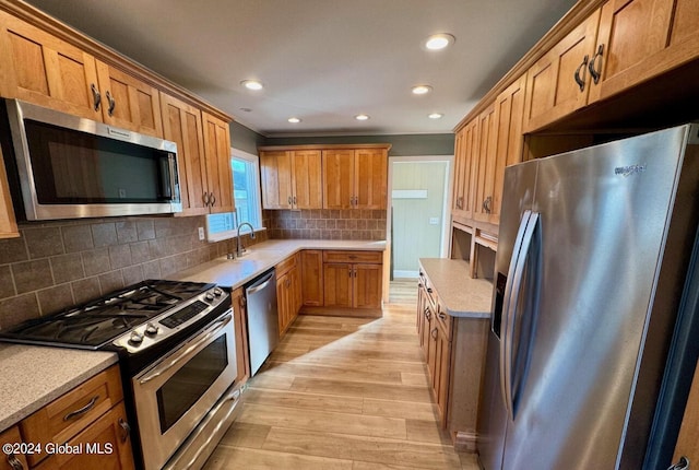 kitchen featuring sink, backsplash, light wood-type flooring, and appliances with stainless steel finishes