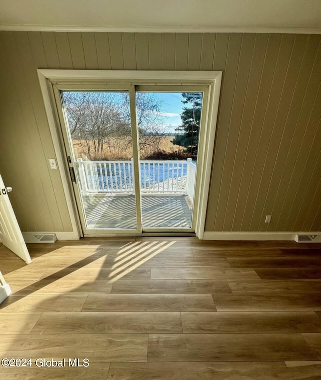 doorway featuring crown molding, plenty of natural light, and light wood-type flooring