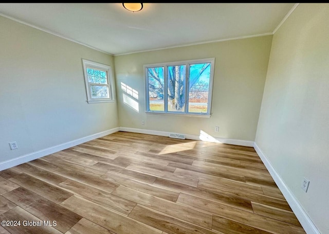 spare room with crown molding, a healthy amount of sunlight, and light hardwood / wood-style floors