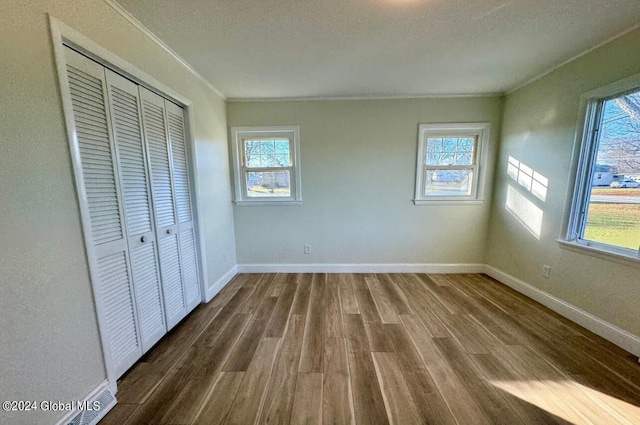 unfurnished bedroom featuring ornamental molding, wood-type flooring, a closet, and a textured ceiling