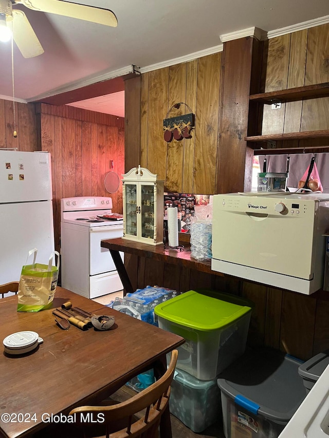 kitchen featuring ornamental molding, ceiling fan, white appliances, and wood walls